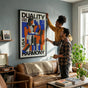A diverse couple adjusting a 24x36 inch geometric love print in a cozy, sun-lit shared American living room, visualizing the poster's large scale