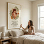 Large framed motherhood poster hanging above a bed in a neutral tone minimalist bedroom